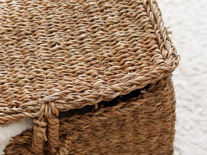 Un grand panier souple en fibres torsadées, couvercle posé de biais, anses courtes.